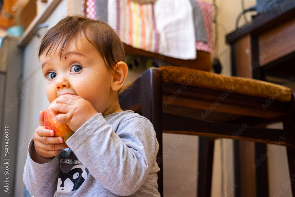 Little baby boy try to eat first supplement organic food - ripe apple, sit on floor. Little baby boy try to eat first supplement organic food - ripe apple, sit on floor.
