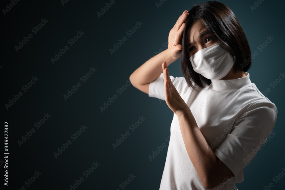 Don't touch me. Asian woman wearing hygiene mask panic and disguted showing hand stop sign and standing isolated over blue background. Health care concepts.