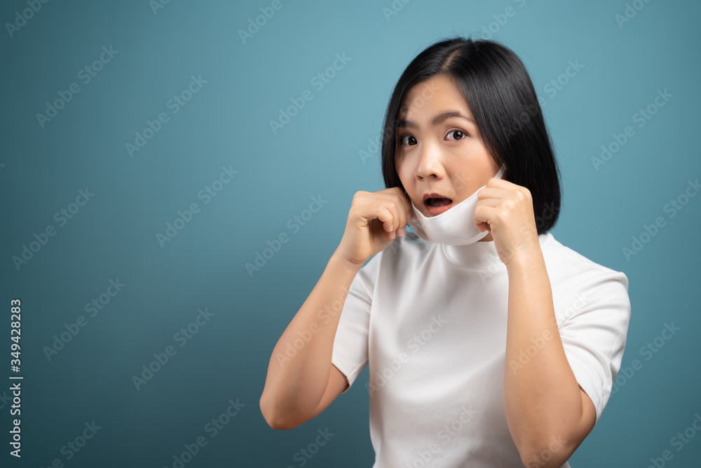 Asian woman wearing protective mask for protection from virus and disease isolated on blue background. COVID-19, Coronavirus concepts.