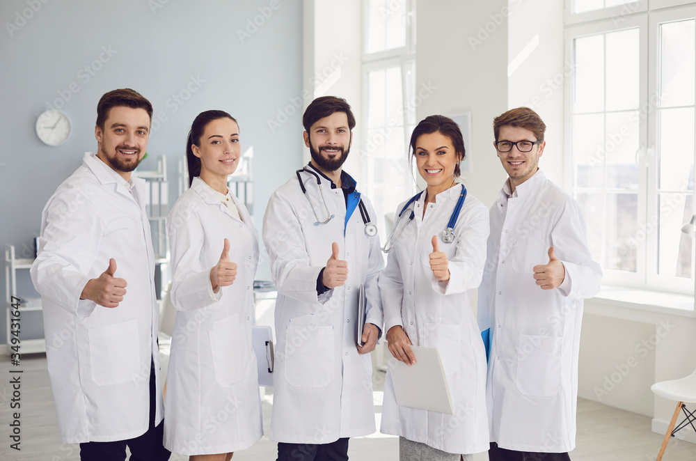Group of practicing doctors with stethoscope are smiling while standing in the clinic office. Group of practicing doctors with stethoscope are smiling while standing in the clinic office.