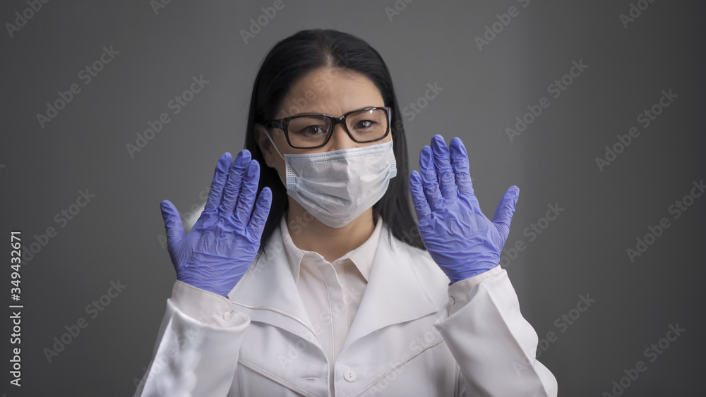 Tired female doctor wearing white uniform raised her hands in disposable gloves. Medical worker is ready to save the sick people. Medicine and healthcare concept Tired female doctor wearing white uniform raised her hands in disposable gloves. Medical worker is ready to save the sick people. Medicine and healthcare concept