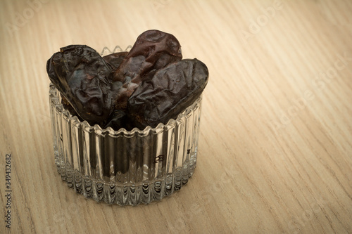 Dates in a small glass container with the sun flare. In Malaysia during Ramadhan month which is fasting month in Islam, dates are very popular because of providing rapid energy through out the day. photo