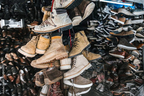 Close-up footwear hanging in the market. Lots of shoes and boots. Beige colors.