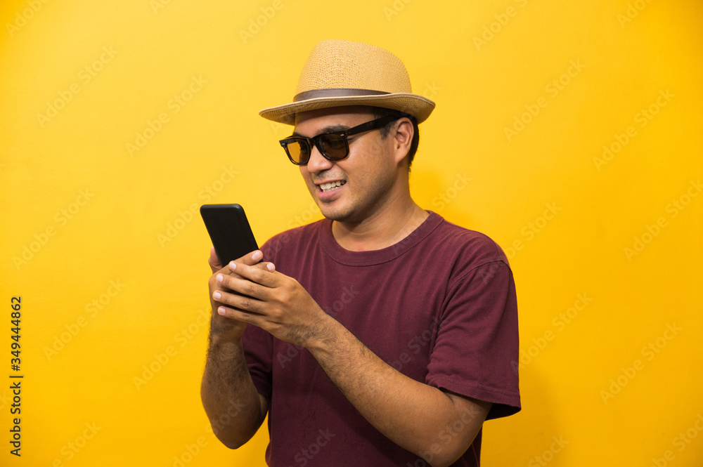 Asian man happy with his smartphone on yellow background. young man using looking at smartphone. Asian man happy with his smartphone on yellow background. young man using looking at smartphone.
