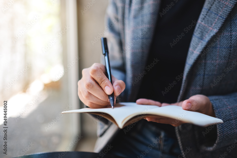 Closeup image of a businesswoman holding and writing on a notebook Closeup image of a businesswoman holding and writing on a notebook