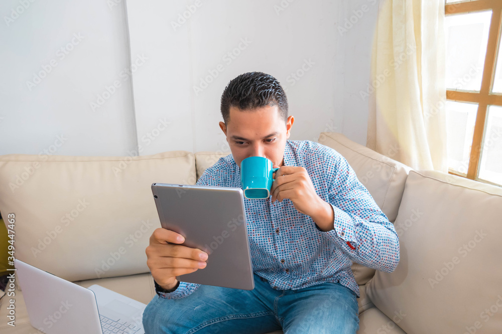 A man reading a message about an online contest on a digital tablet while drinking coffee A man reading a message about an online contest on a digital tablet while drinking coffee