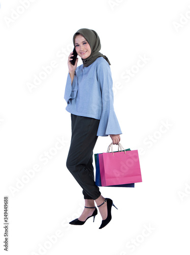 Beautiful women of muslim Indonesian do phone call and carrying a shopping bag isolated on white background