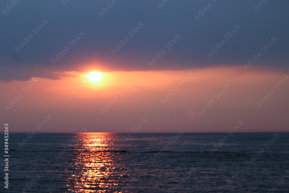 Beautiful orange sunset or sunrise near seaside ocean dark colors