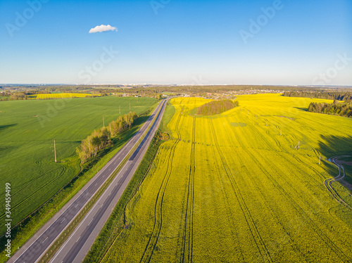 Yellow field and the road in the sunset light. Drone aerial photo from Belarus