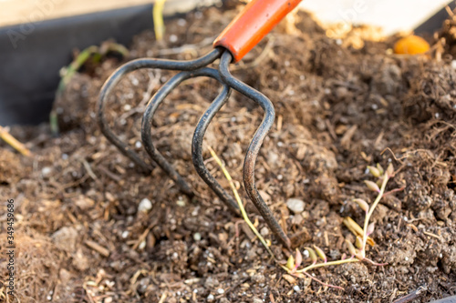 A closeup view of a garden cultivator tool on a pile of dirt.
