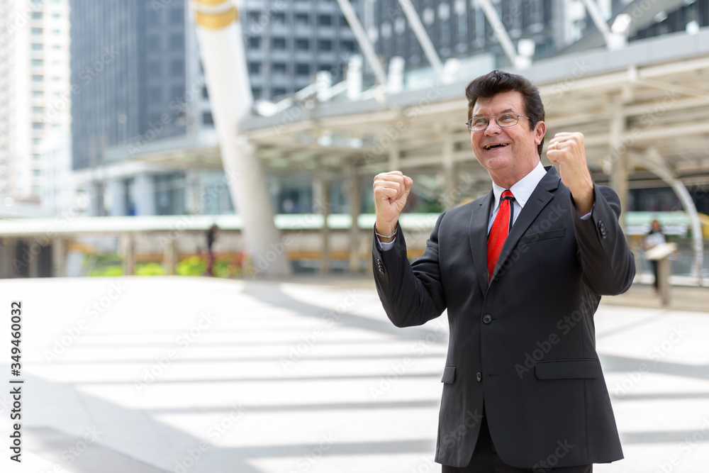 Mature happy businessman in front of modern building at Bangkok city Mature happy businessman in front of modern building at Bangkok city