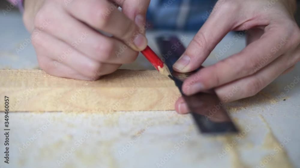 Carpenter hands make markings with pencil on a wooden plank Carpenter hands make markings with pencil on a wooden plank