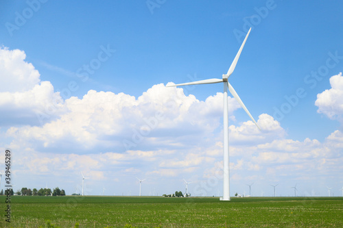 A white windmill in the middle of the meadow in a sunny day with clear blue sky