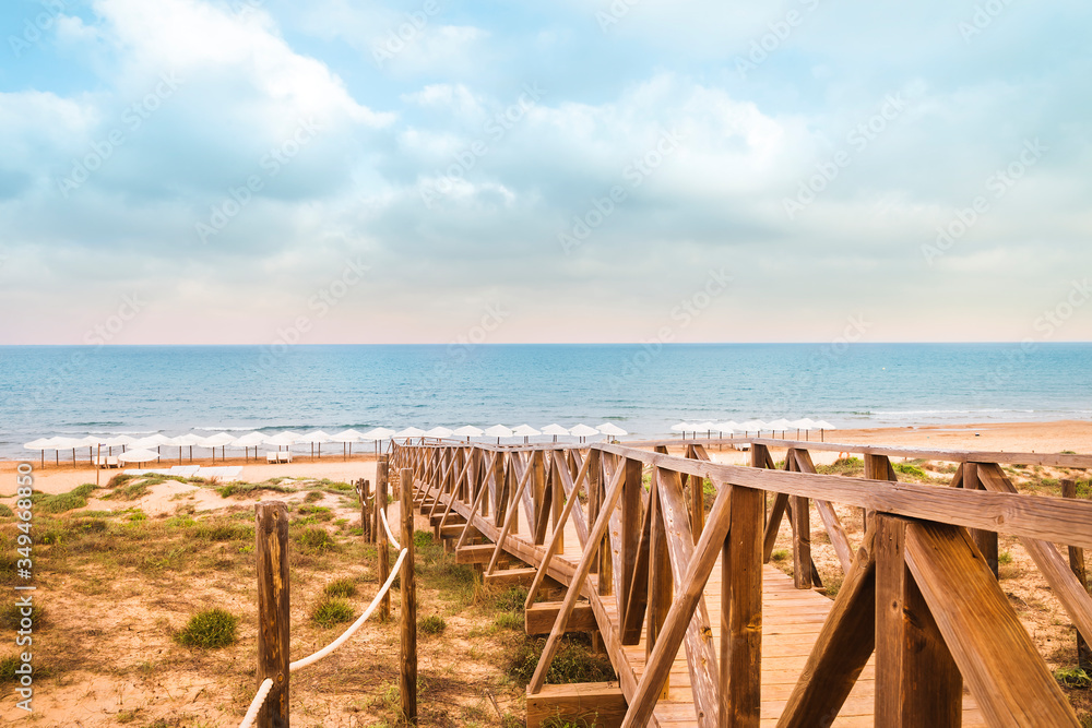 landscape of wooden footbridge to access the beach in summer . Guardamar, Alicante, Spain