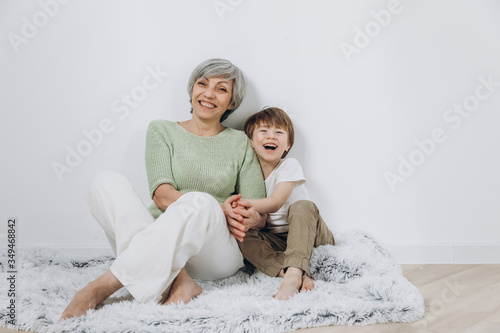 A little boy and his grandmother are having fun together against a light background