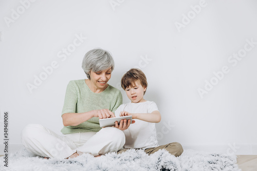 A little boy and his grandmother are having fun together against a light background