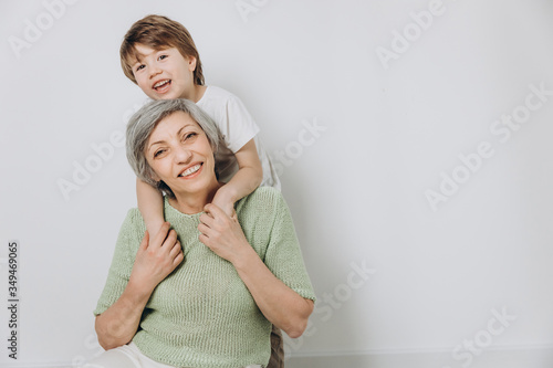 A little boy and his grandmother are having fun together against a light background