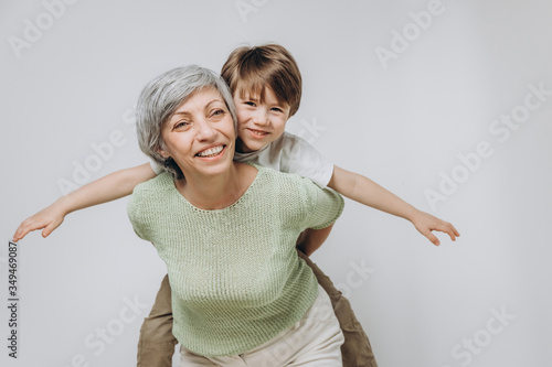 A little boy and his grandmother are having fun together against a light background
