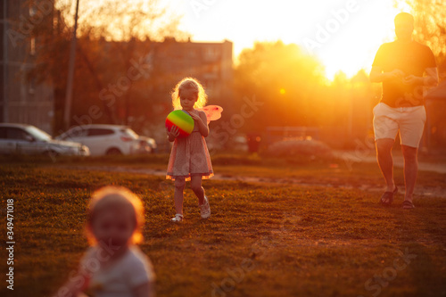 little girl plays with a multi-colored ball on the playground at sunset at golden hour. Low key photo
