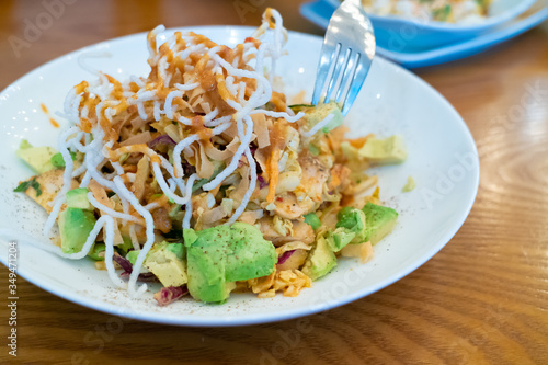 Avocado salad with crunchy noodles on top and fork.