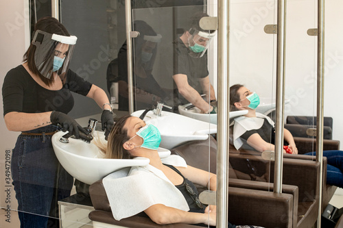 Servizio di lavaggio capelli dentro un salone da parrucchieri con tutte le disposizioni di protezione quali mascherine facciali,  photo
