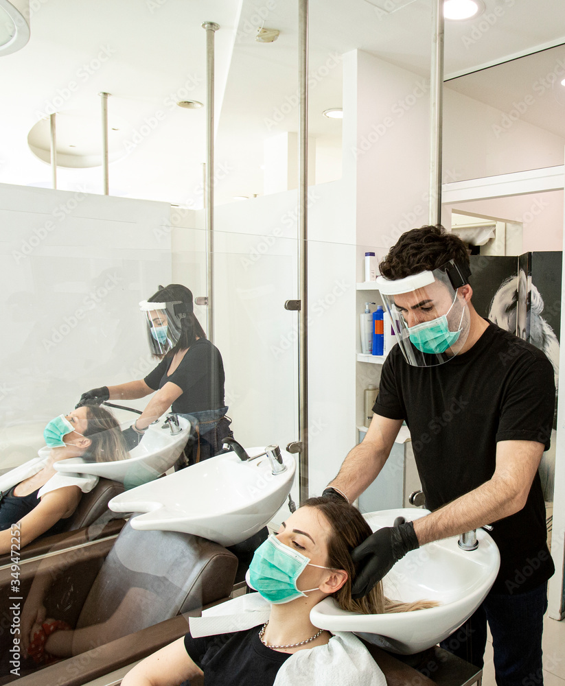 Servizio di lavaggio capelli dentro un salone da parrucchieri con tutte le disposizioni di protezione quali mascherine facciali,  - obrazy, fototapety, plakaty 