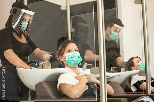 Servizio di lavaggio capelli dentro un salone da parrucchieri con tutte le disposizioni di protezione quali mascherine facciali,  photo