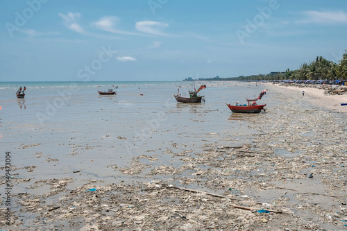 Boats floating on sea with a lot of plastic bottle and garbage on dirty beach - water environment pollution concept