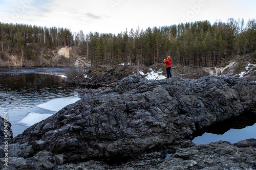 a man stands on a lava rock on the background of the melted pond and trees