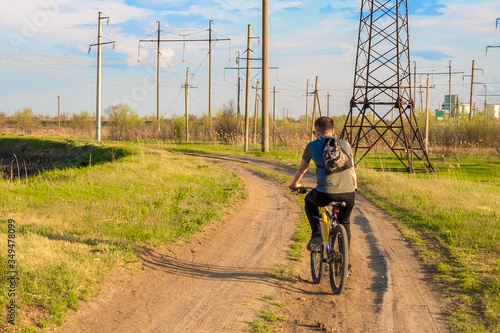 A man traveling on a Bicycle rides on a dirt road in a rural area. Healthy active lifestyle of the traveler.