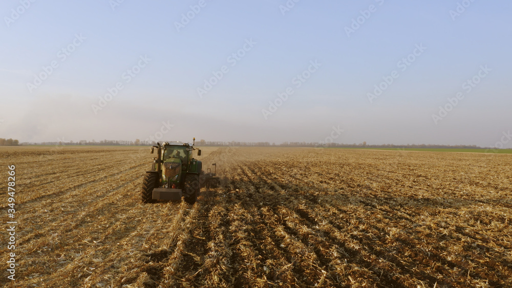 Fototapeta premium Green tractor working on field. Tractor plow field. Modern agrictulture machinery.