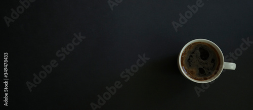 Black background with a cup of coffee. Flat lay