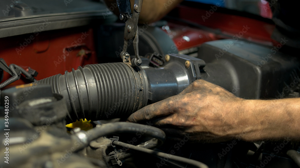 Close up worker installing car engine hose. Mechanic assembling car mechanism.