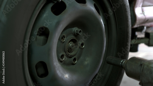 Close up man unscrewing car wheel. Removing nuts using electrical screwdriver.