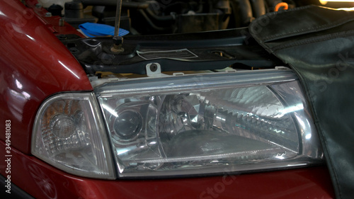 Close up car headlight with opened hood. Enginge repair in a car service.