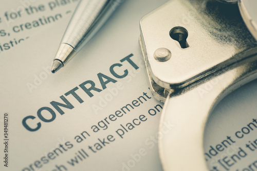 Fotografi Pen and a handcuff on a legal contract form, depicting a contract was signed by a coerced or forced person at gunpoint
