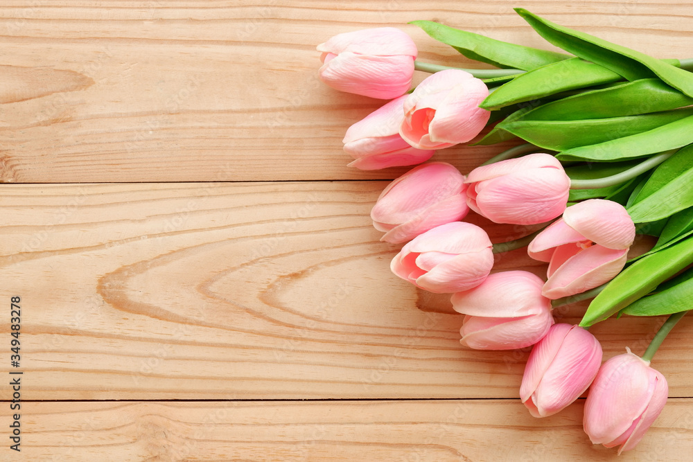 Yellow and pink tulips placed on a wooden table.