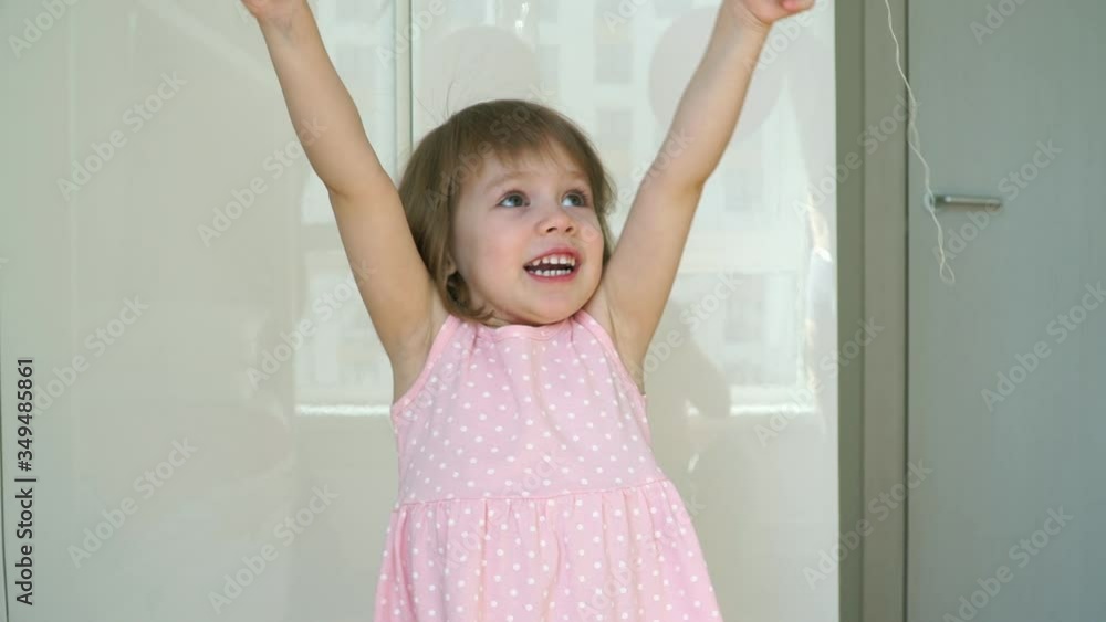 Portrait of little cute 3 year old smiling girl celebrates birthday with pink balloon, looks at camera and laughs. Happy child plays with air balloons. Portrait of little cute 3 year old smiling girl celebrates birthday with pink balloon, looks at camera and laughs. Happy child plays with air balloons.