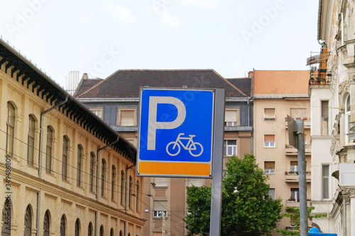 Signs of bicycle parking on background of city. Inscription parking on metallic blue plate. © Ga_Na