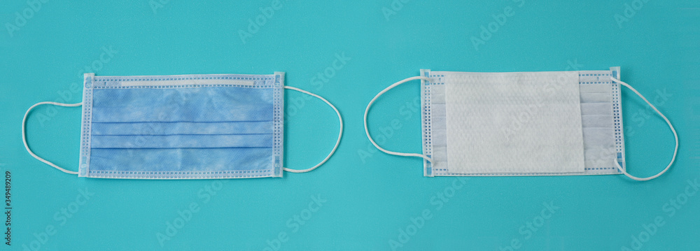 Two pieces of blue face mask are on blue background.  The right one show a white filter material. The items are necessary to prevent Corona virus (Covid-19) during pandemic in 2020.  Flat lay.