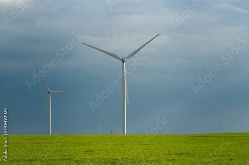 Landscape view of wind power turbine among green meadow with sky in the morning and copy space for text in the sky. Green energy concept.