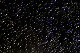 Night. raindrops on dark glass illuminated by a lantern. Concept - background, image of the starry sky.