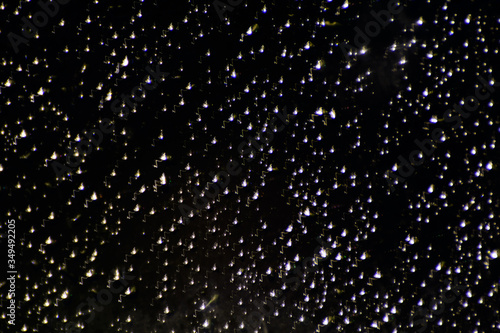 Night. raindrops on dark glass illuminated by a lantern. Concept - background, image of the starry sky.