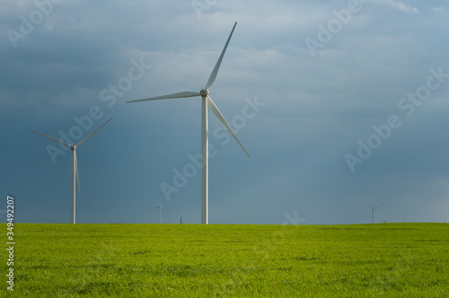 Landscape view of wind power turbine among green meadow with sky in the morning and copy space for text in the sky. Green energy concept.