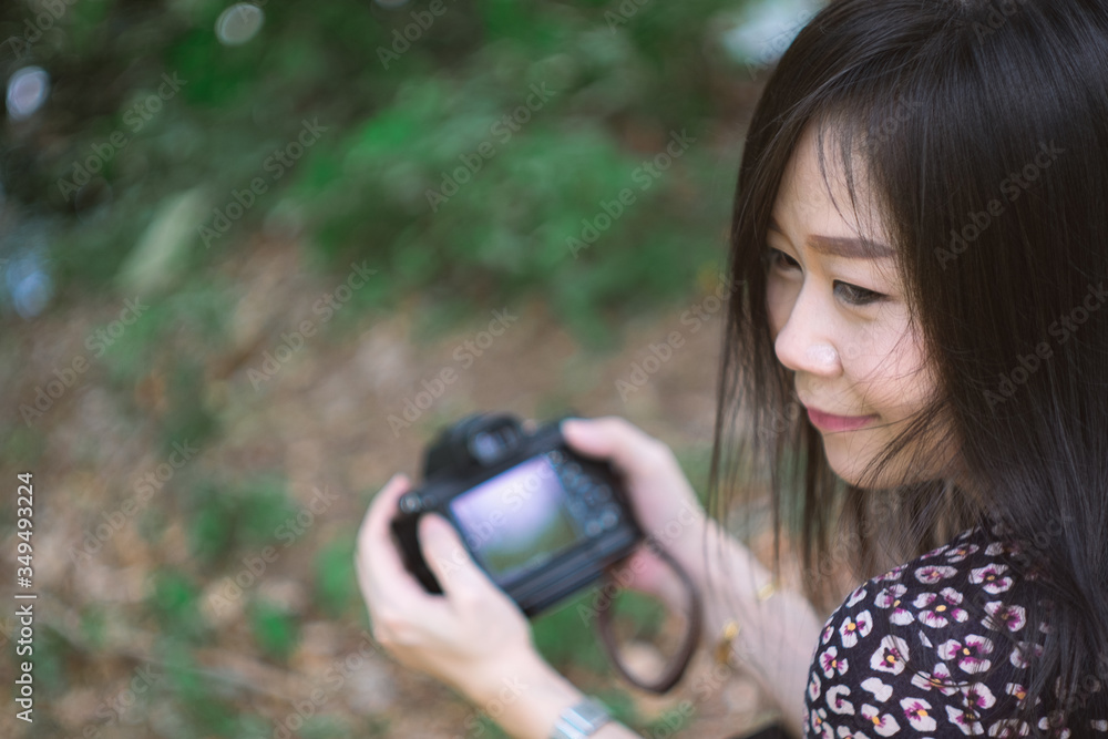 Fototapeta premium Portrait of beautiful smiling asian woman with holding camera at summer green park.