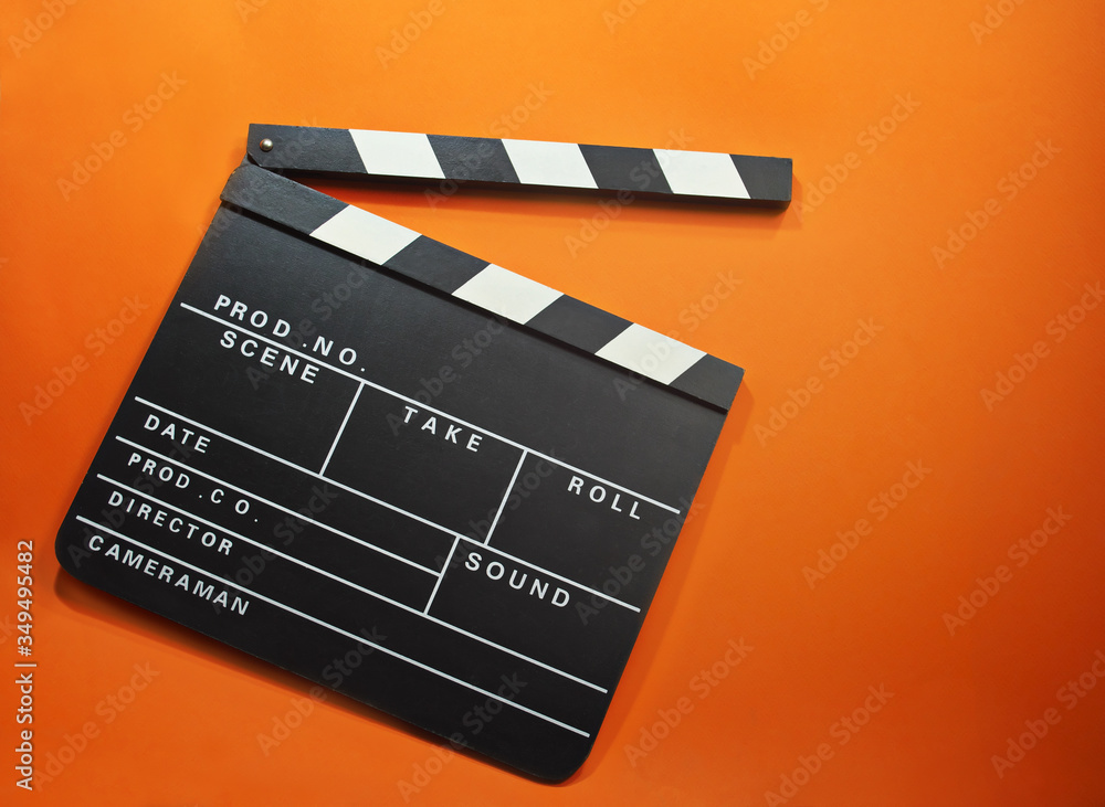 Flat lay an open film clap board with a bright orange background