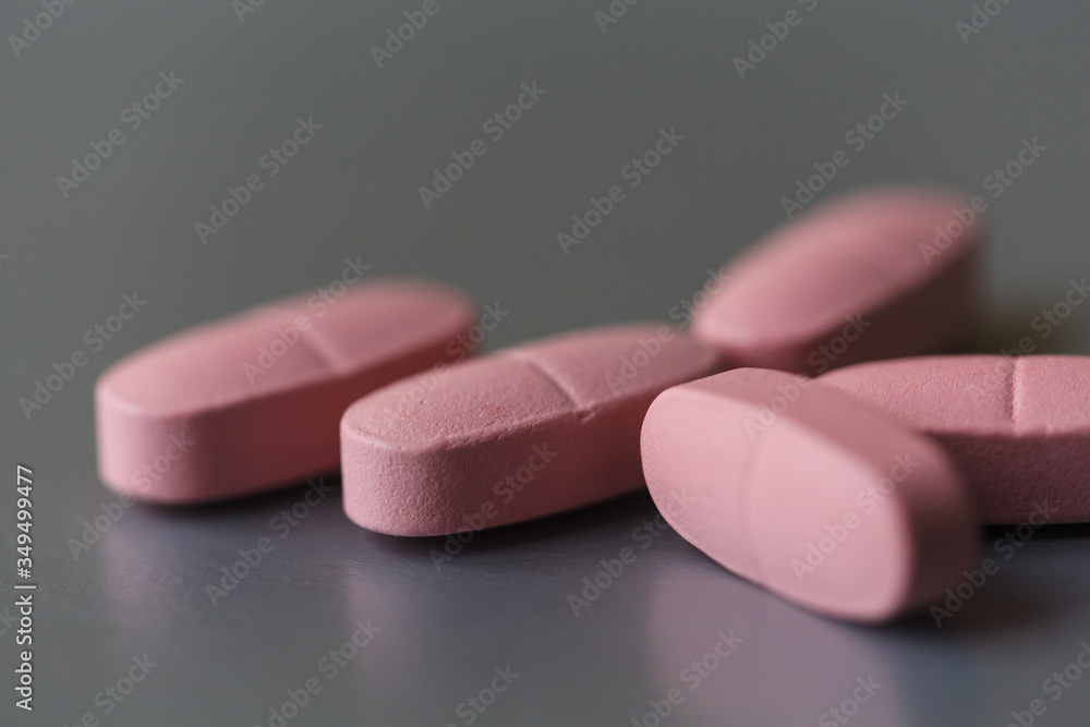 Long pink pills on the silver background. Selective focus, shallow depth of field Long pink pills on the silver background. Selective focus, shallow depth of field