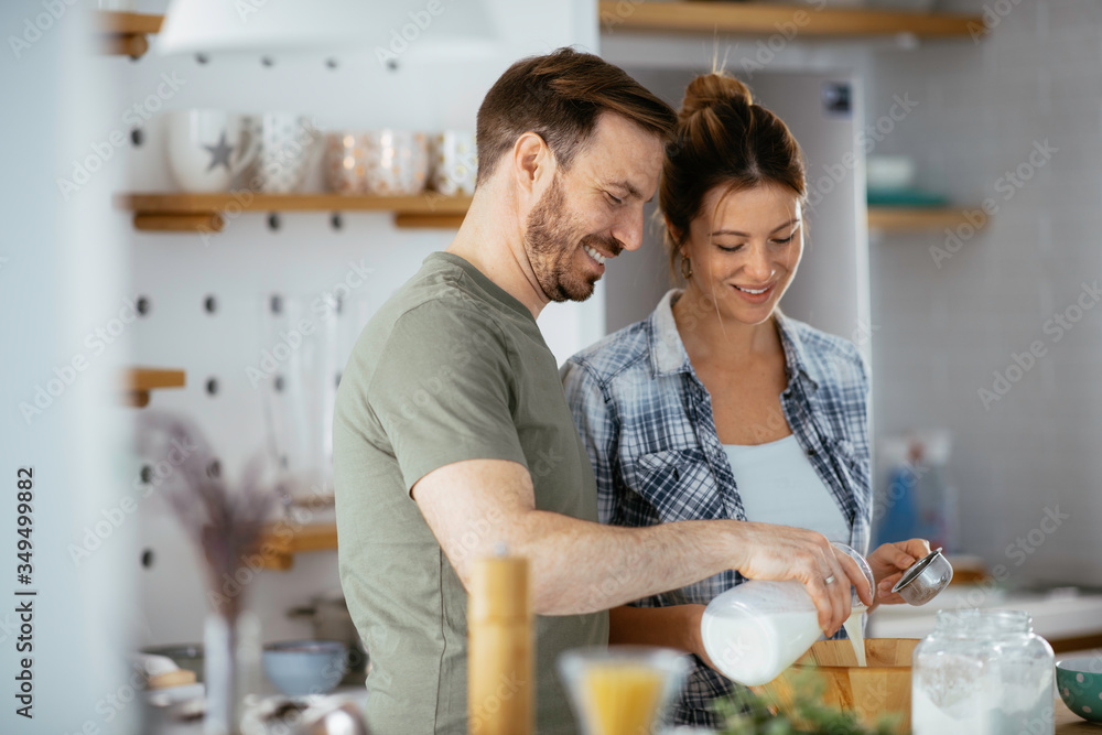 Young couple making pancakes at home. Loving couple having fun while cooking. Young couple making pancakes at home. Loving couple having fun while cooking.