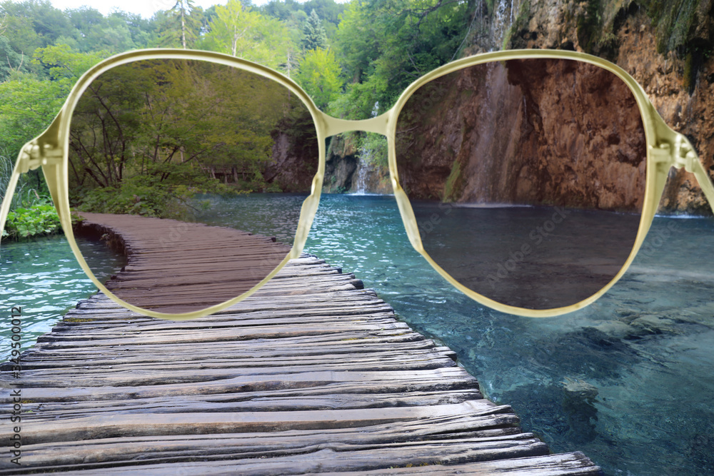Wooden bridge over lake, view through sunglasses