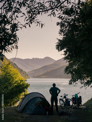 Silhouette of a woman on a wild camping spot in Patagonia with views on a lake and mountains during sunset
